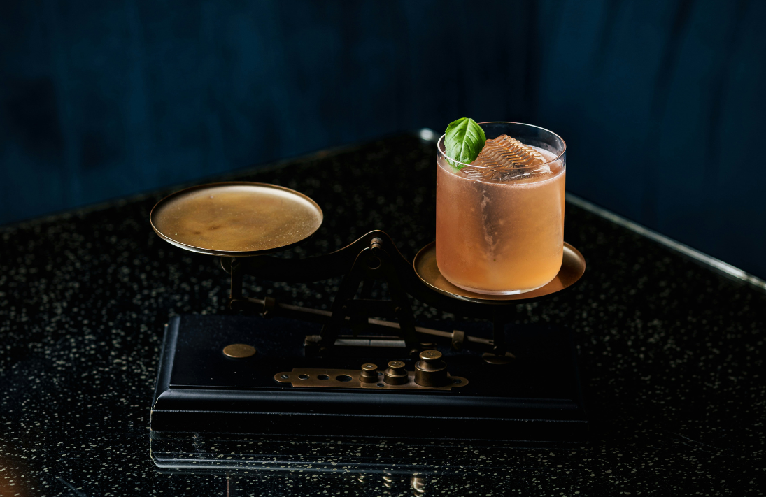 A glass of orange drink on a dark, elegant background