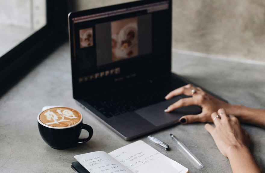 On the left, a coffee with latte art; on the right, a person working with a graphic design program on a computer